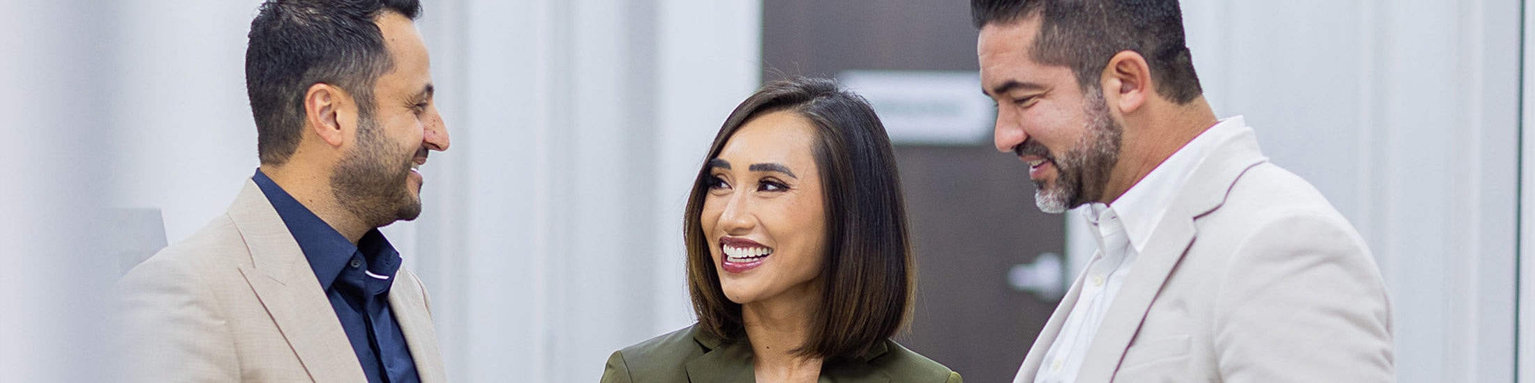 Three professionals engaged in friendly conversation.