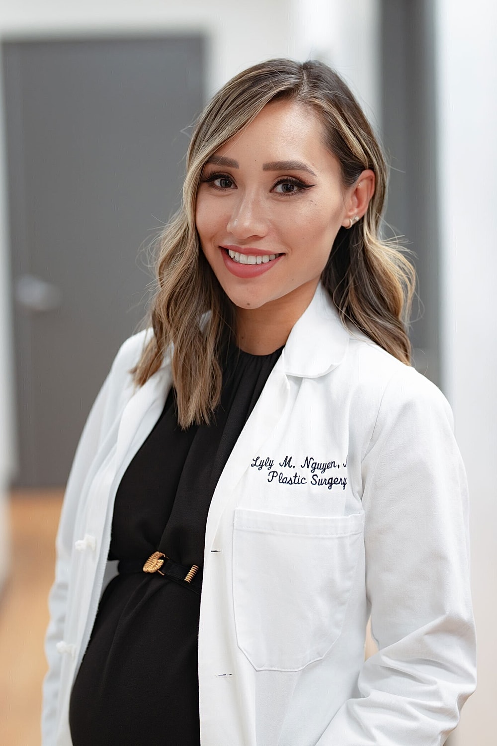 Pregnant doctor in white lab coat smiling.