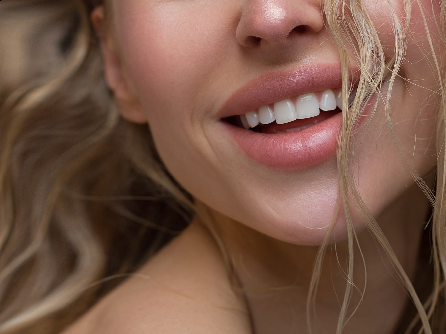 Close-up of smiling woman's face with wavy hair.