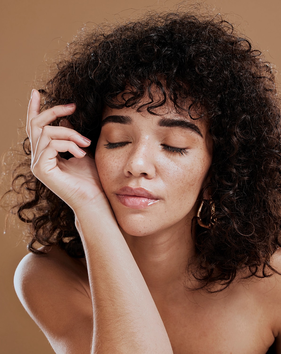 Woman with curly hair and closed eyes.