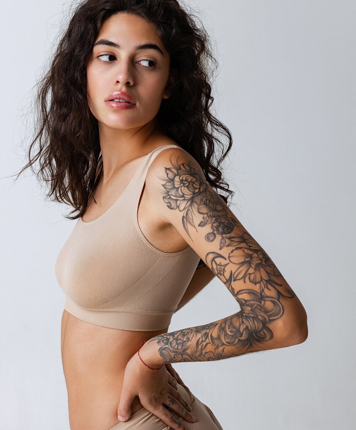 Woman in neutral bra showcasing floral tattoos.