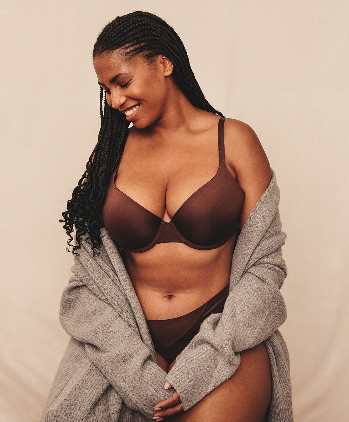 Woman smiling in brown lingerie and sweater.