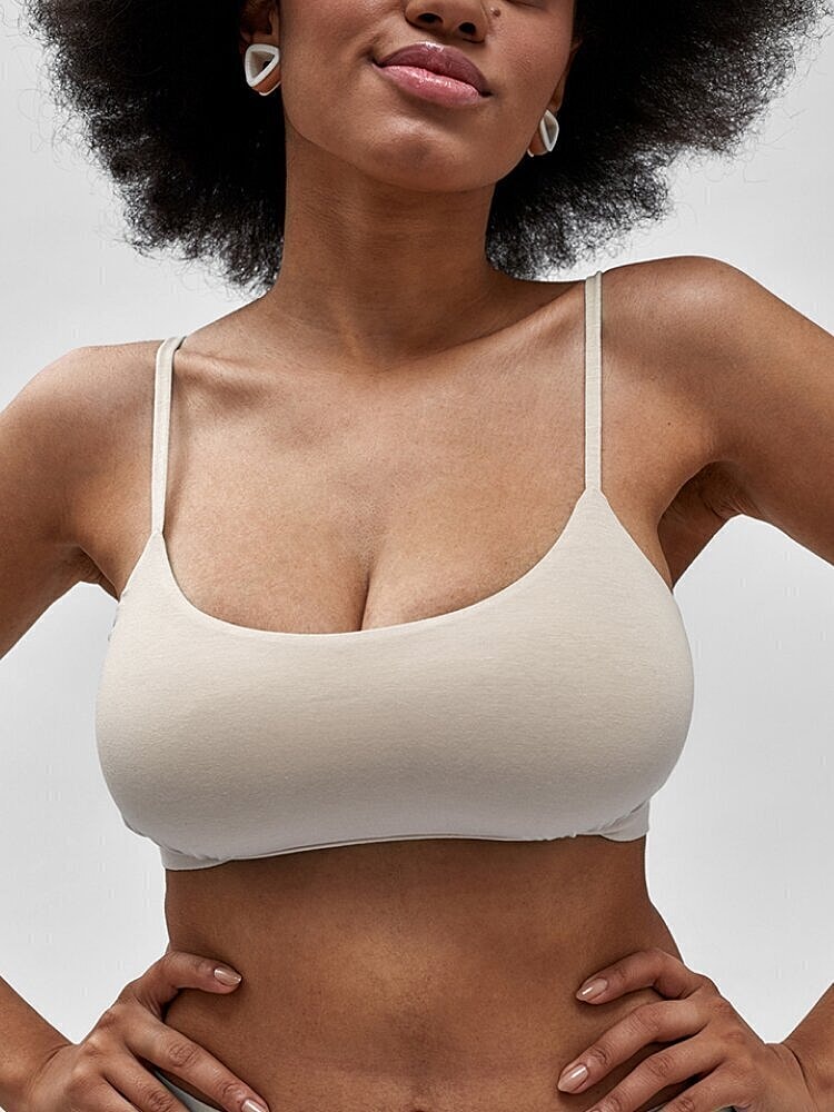 Model wearing light beige bralette with earrings.