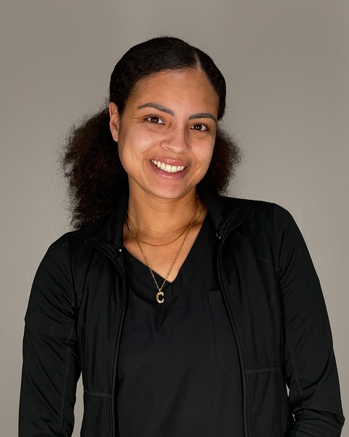 Smiling woman with curly hair and necklace.