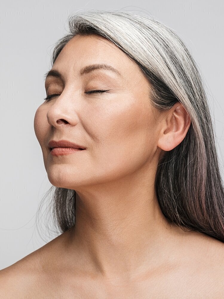 Woman with closed eyes and silver hair.
