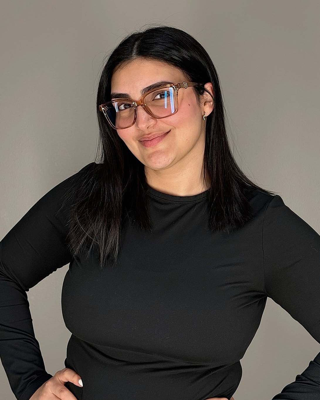 Smiling woman in glasses against plain background.