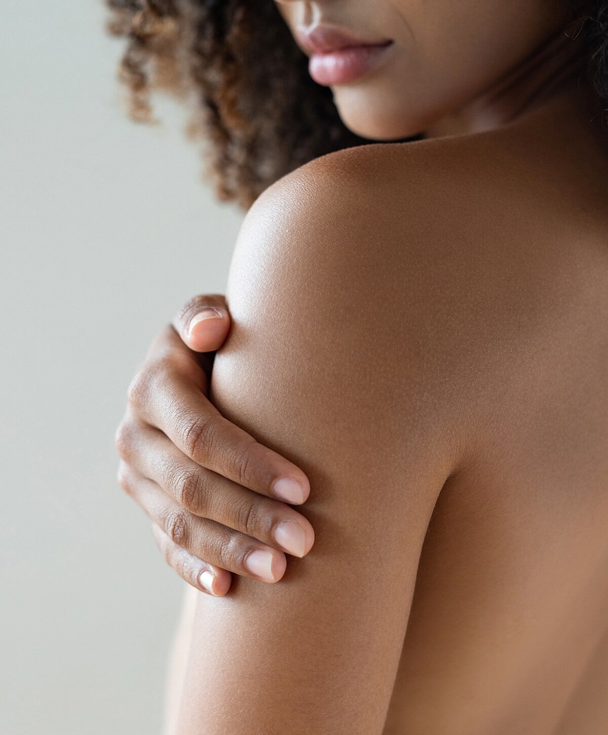 Woman gently holding her shoulder, close-up view.
