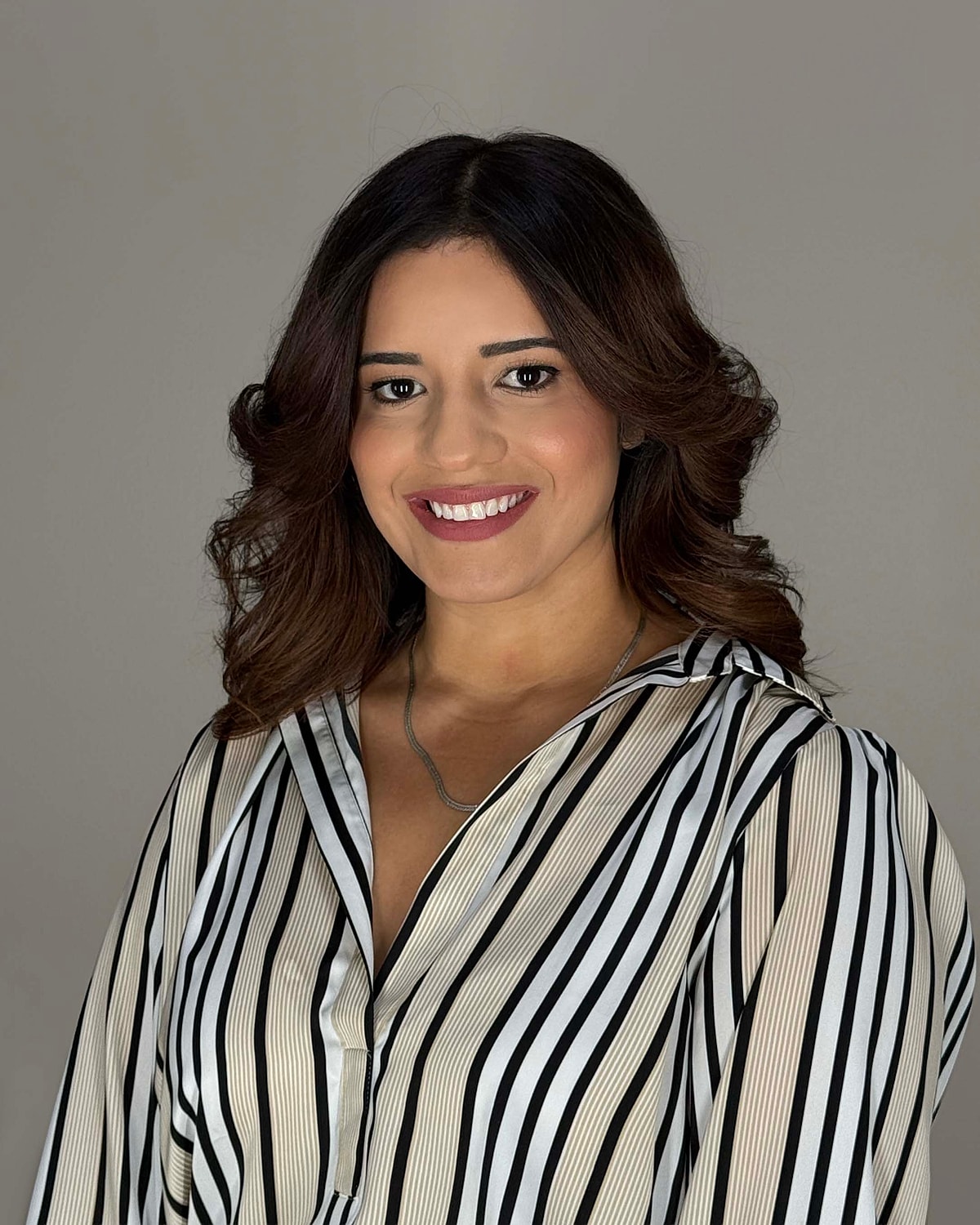 Smiling woman with wavy hair and striped shirt.