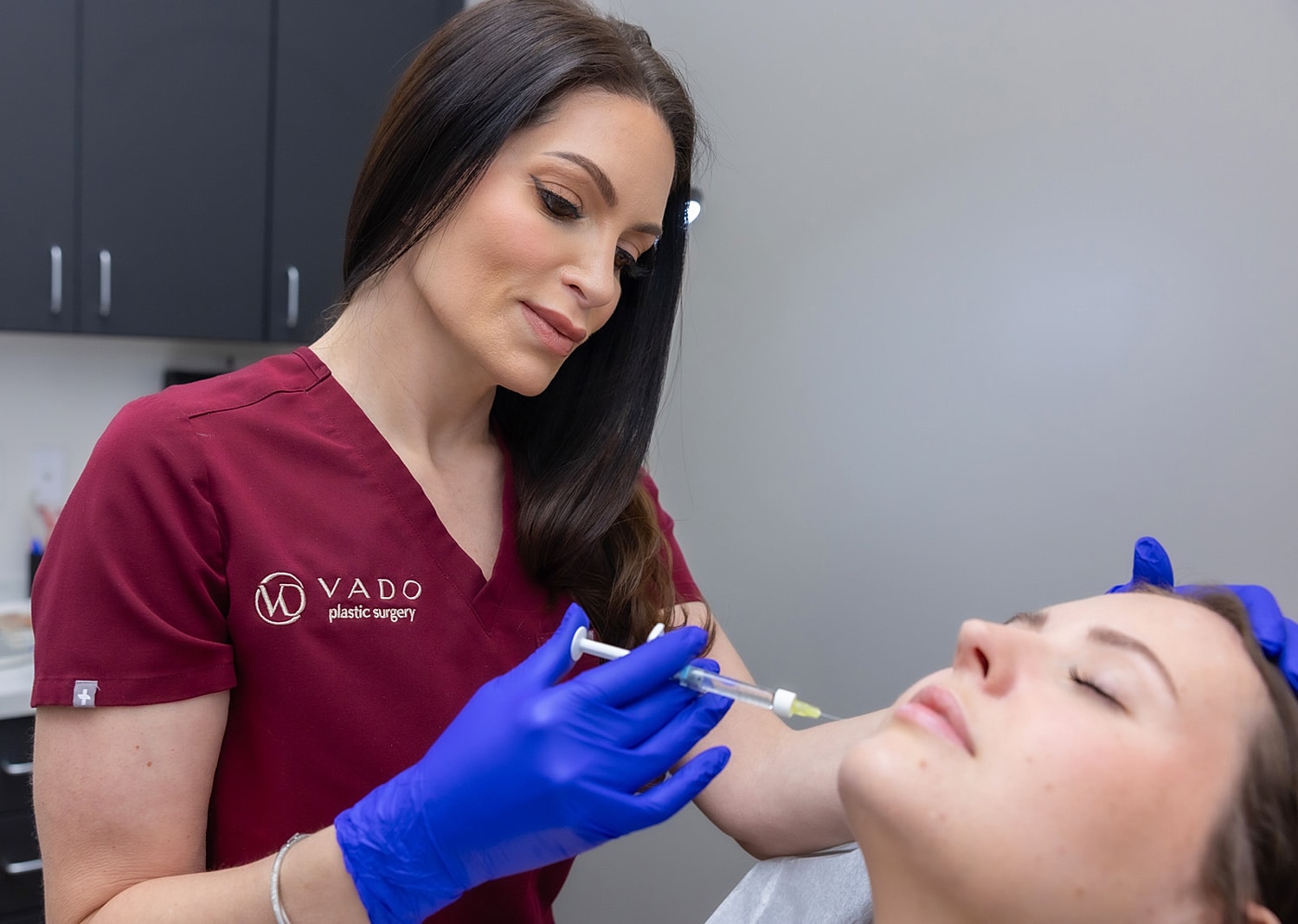 Medical professional administering aesthetic treatment to patient.