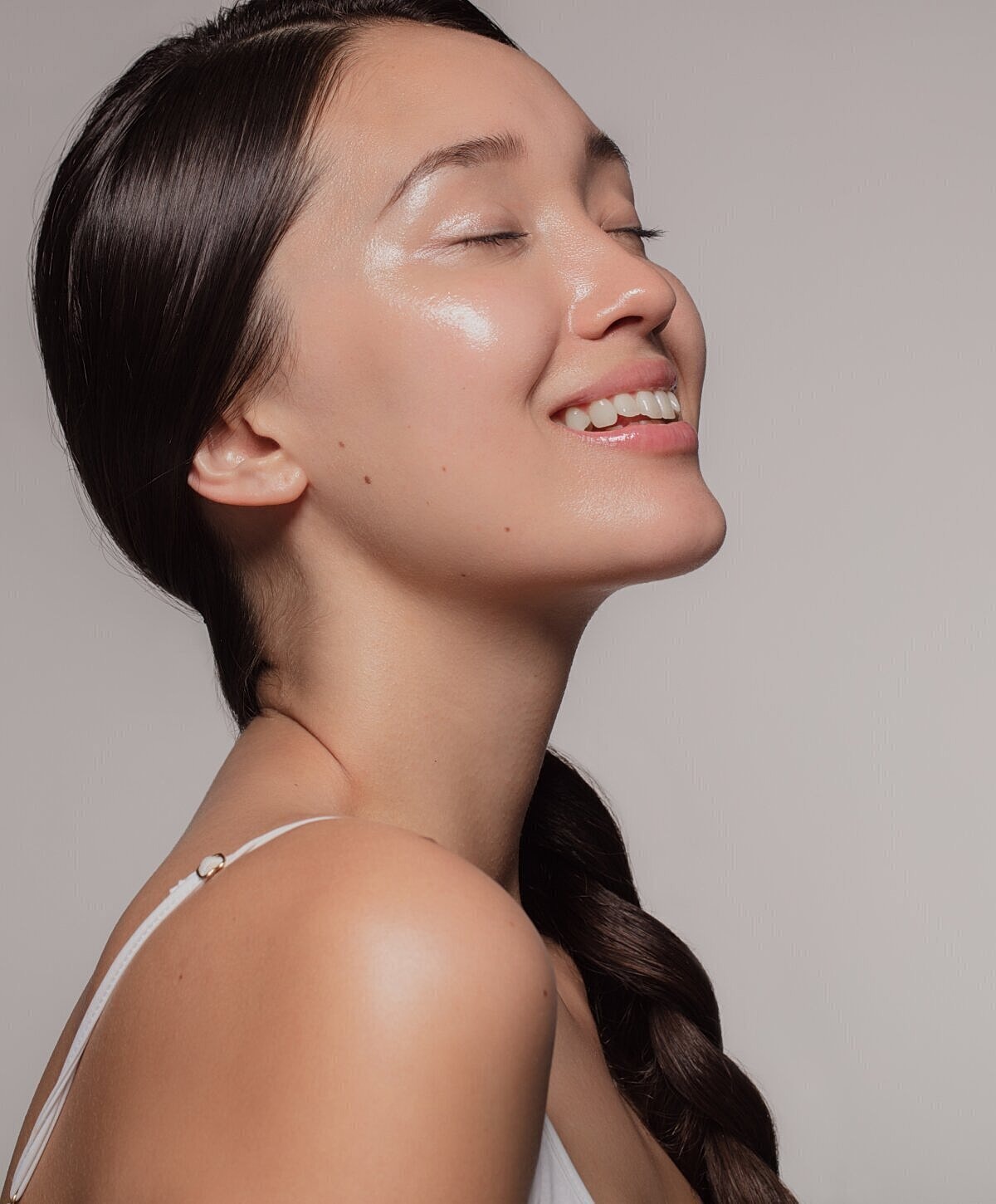 Smiling woman with glowing skin and closed eyes.