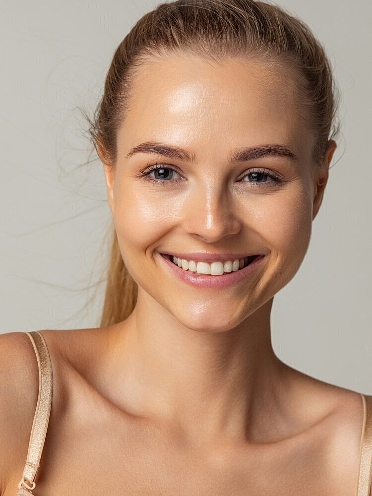 Smiling woman with natural makeup and healthy skin.