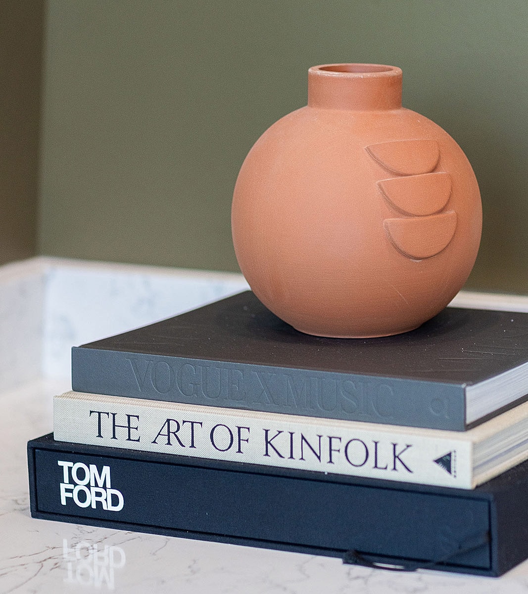Terracotta vase on stacked coffee table books.