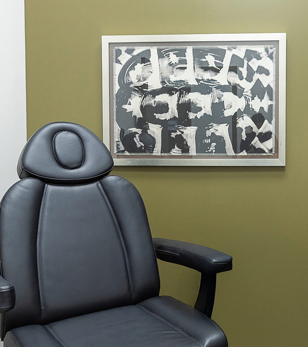 Black chair beside abstract wall art.