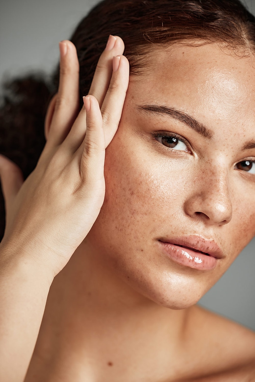 Close-up of freckled face with hand touching cheek.