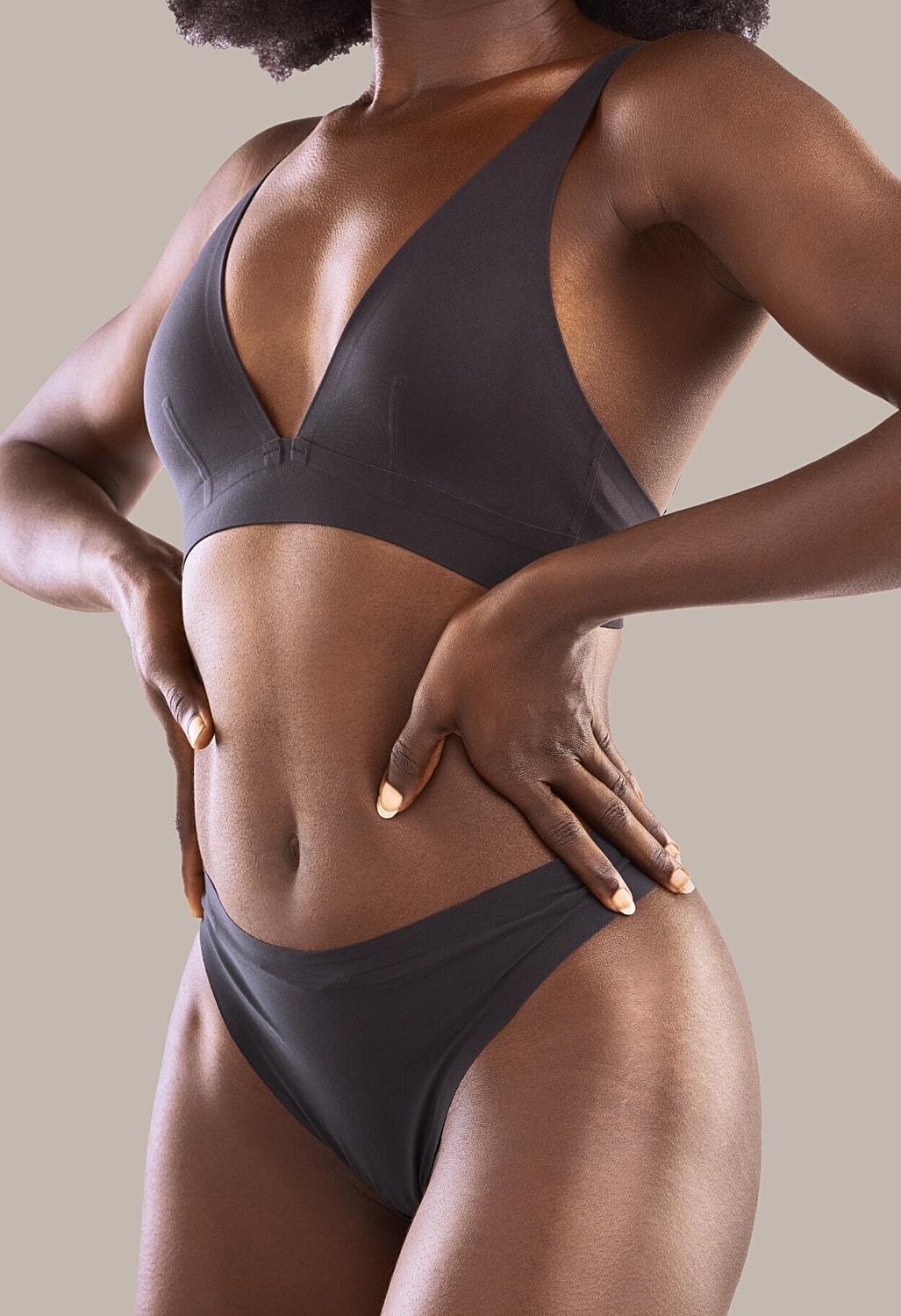 tummy tuck patient model in gray bra and panties with her hands on her waist