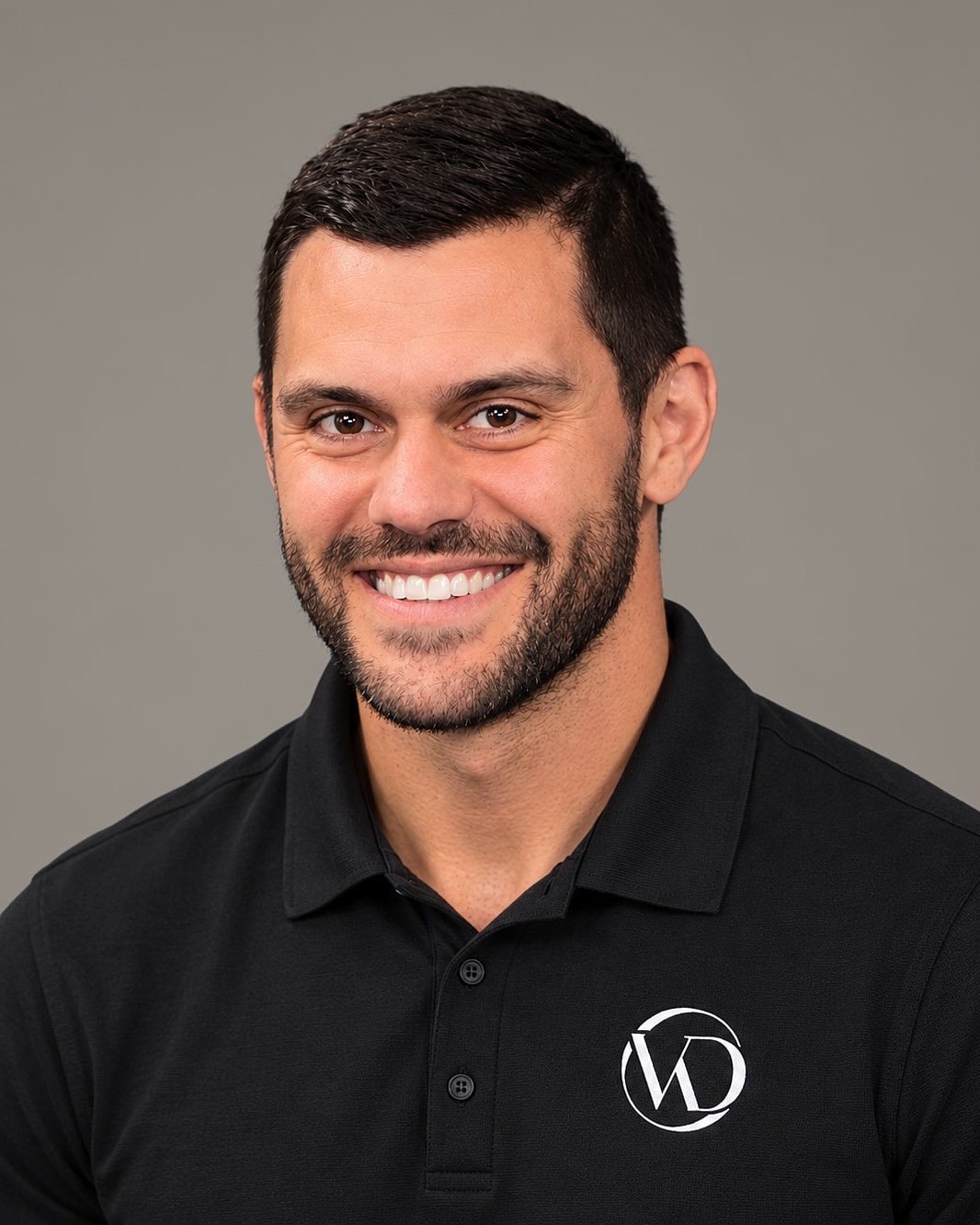 Smiling man in black polo shirt portrait.
