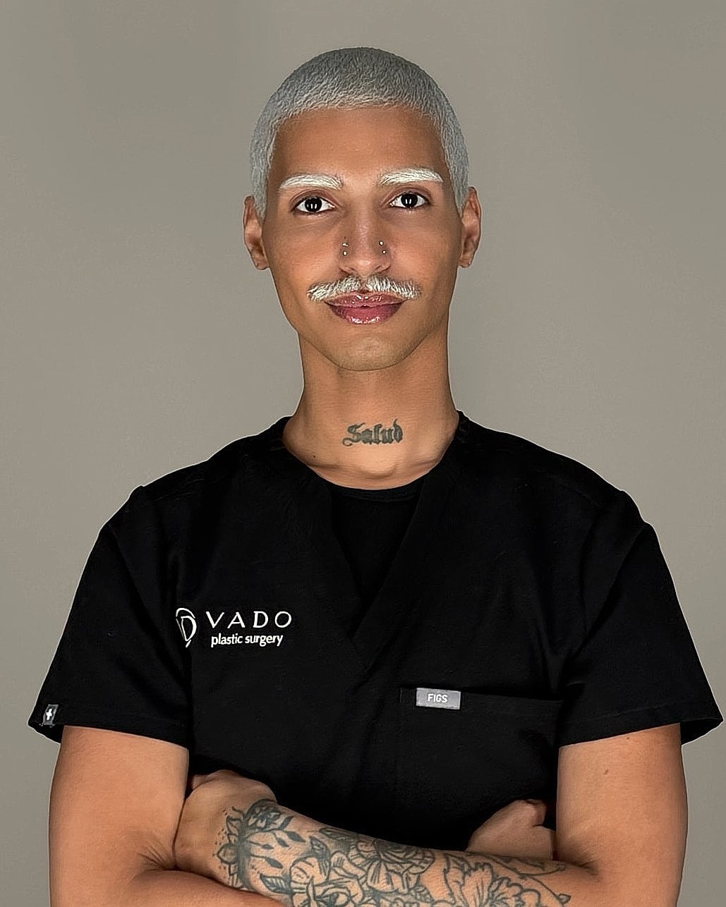 Person in black scrubs with tattoos and confident pose.