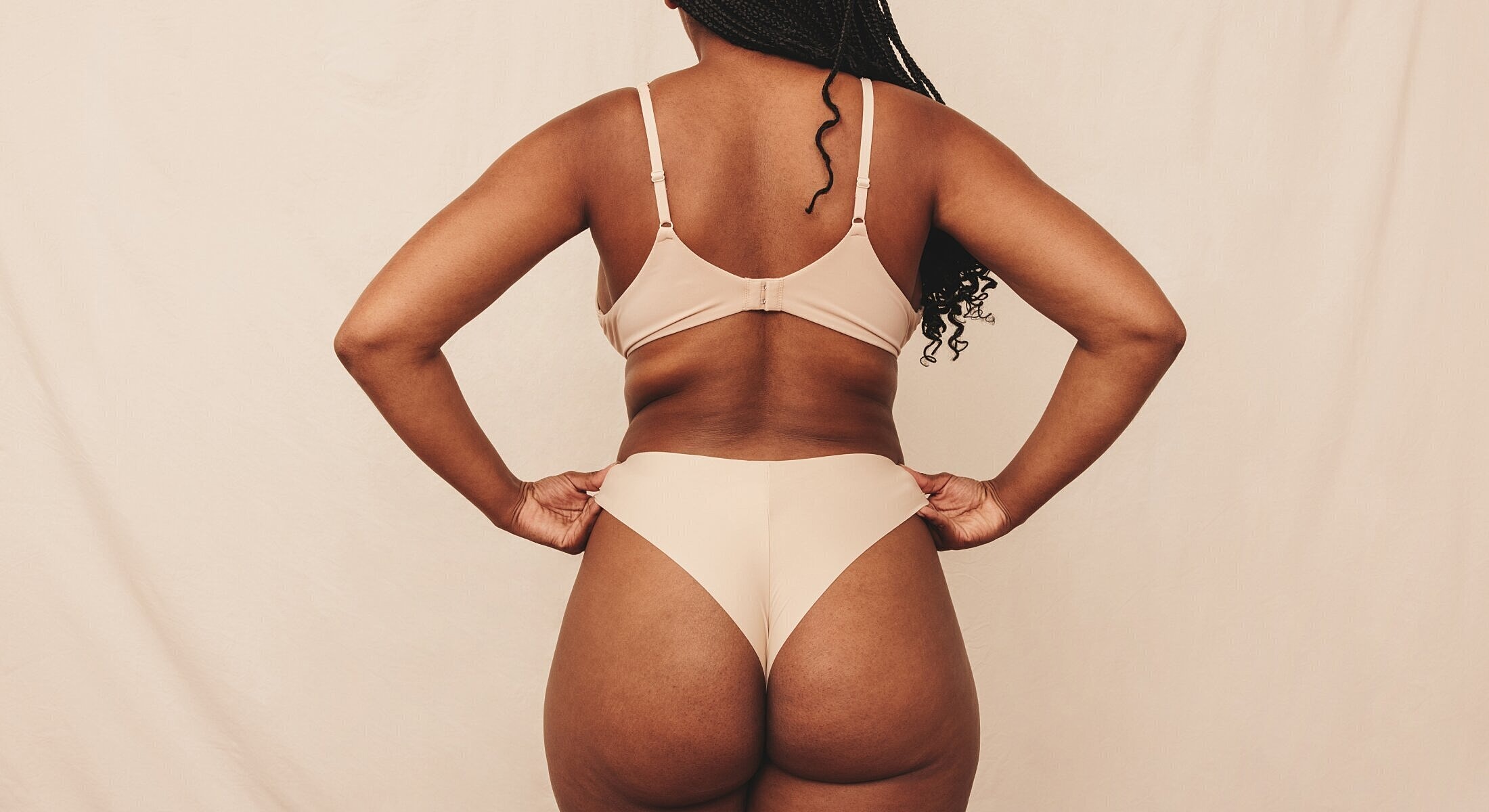 Model wearing beige lingerie against neutral background.