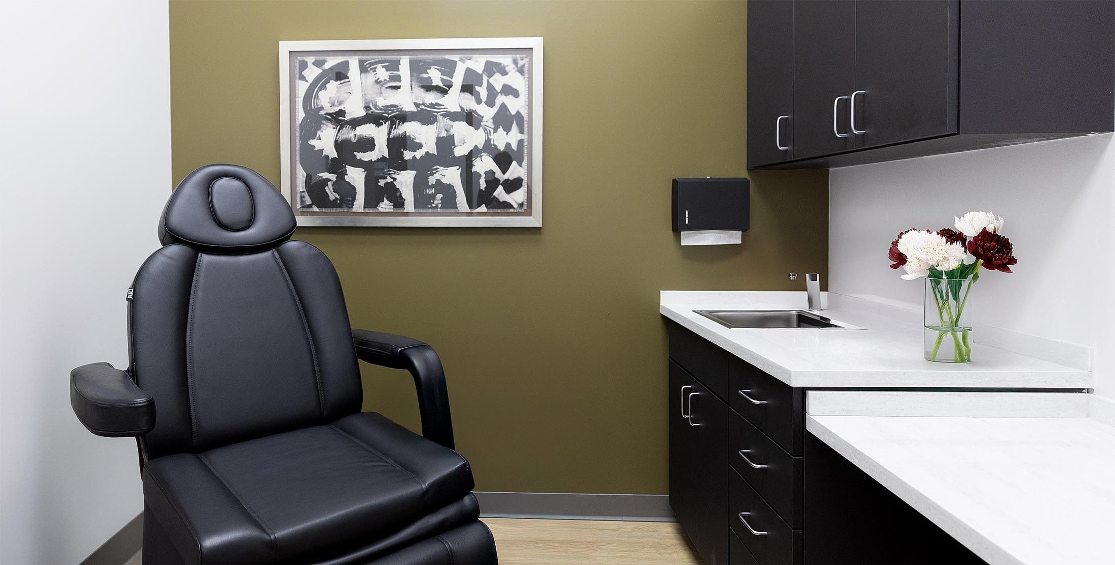 Medical office with black chair and flowers.