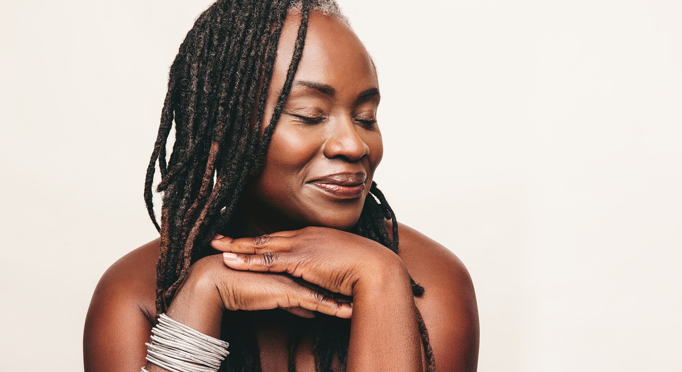Smiling woman with long dreadlocks and jewelry.