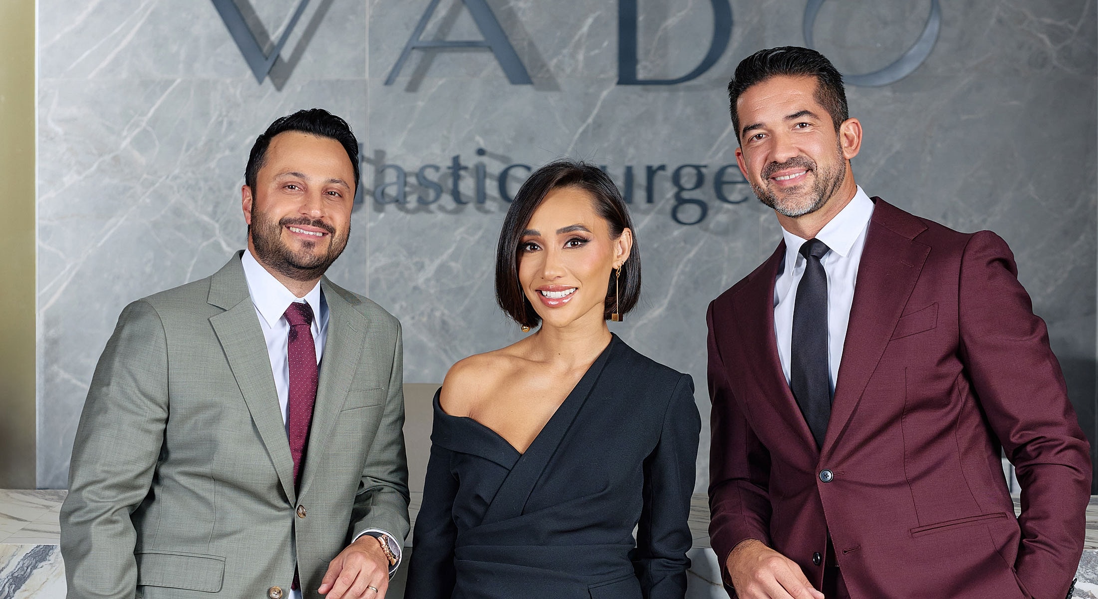 Three professionals in front of VADO sign.