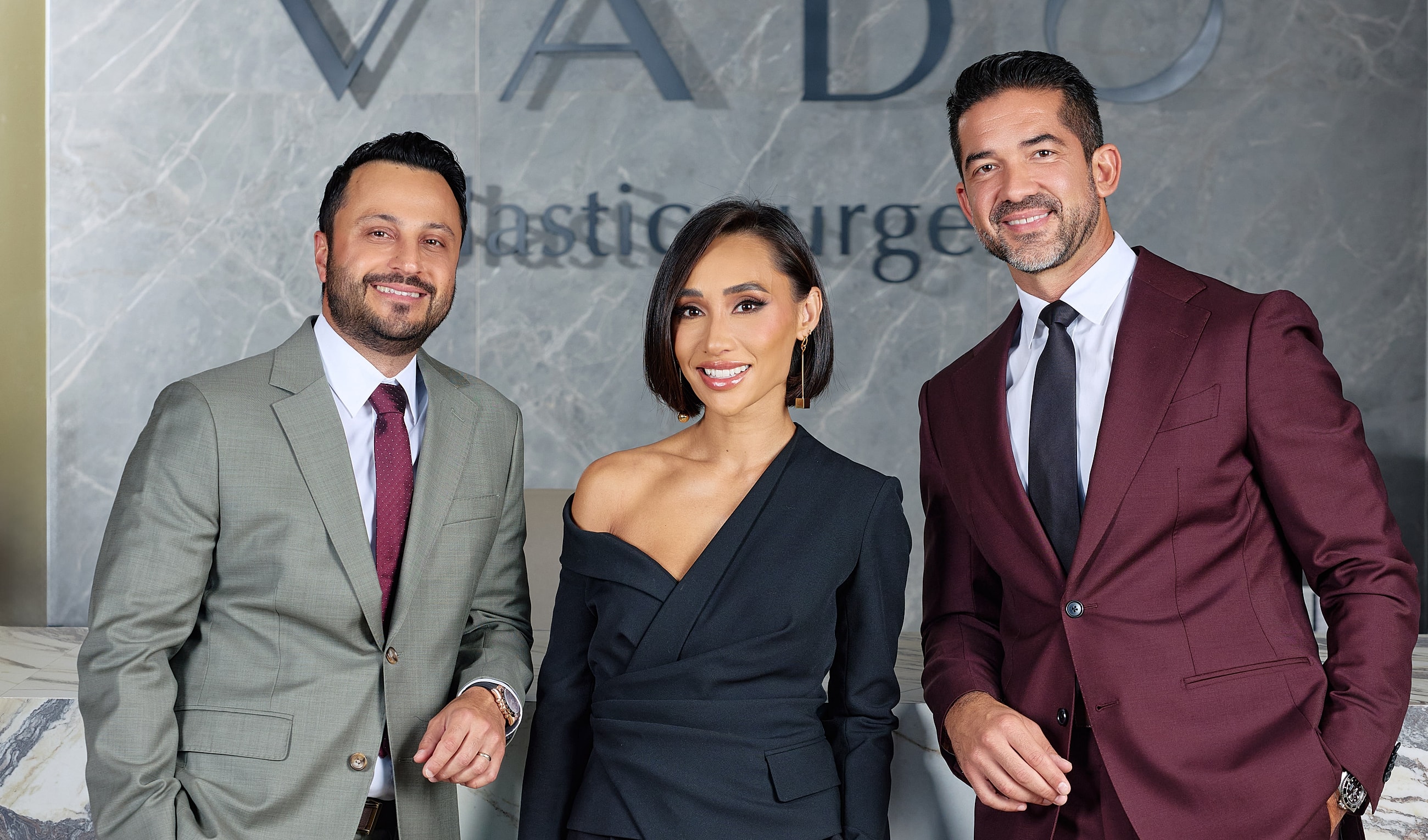 Three professionals posing in a modern office.