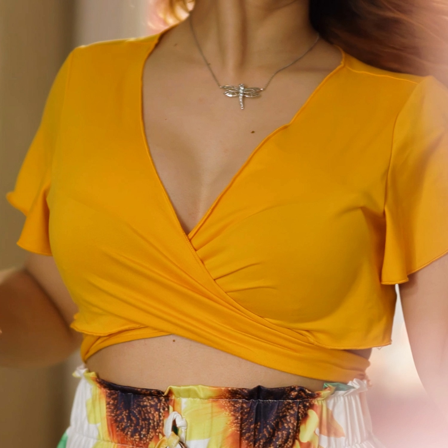 Yellow wrap top with silver dragonfly necklace.