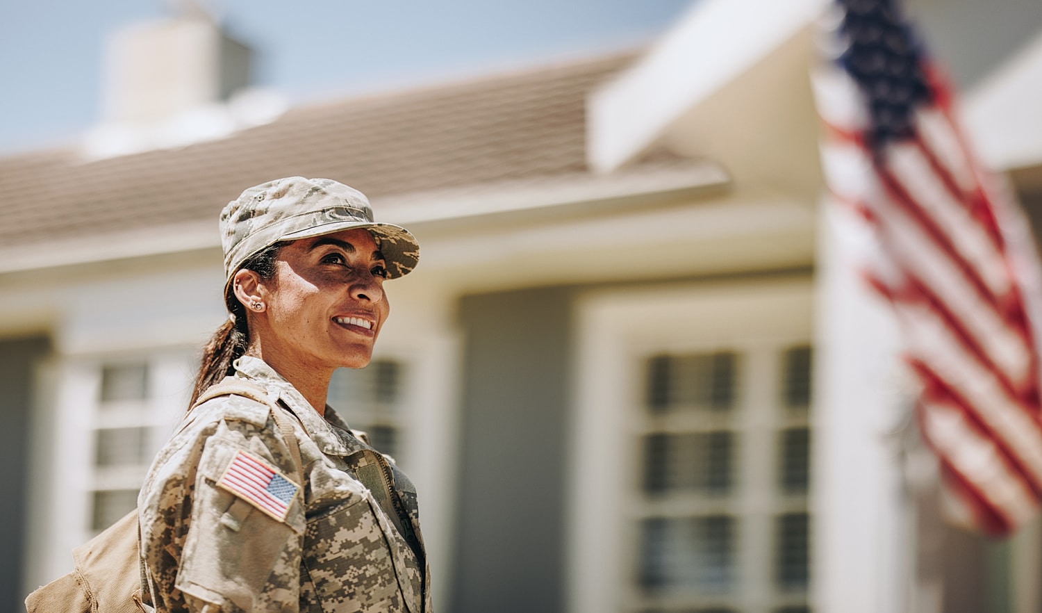 Smiling soldier in uniform outside home.